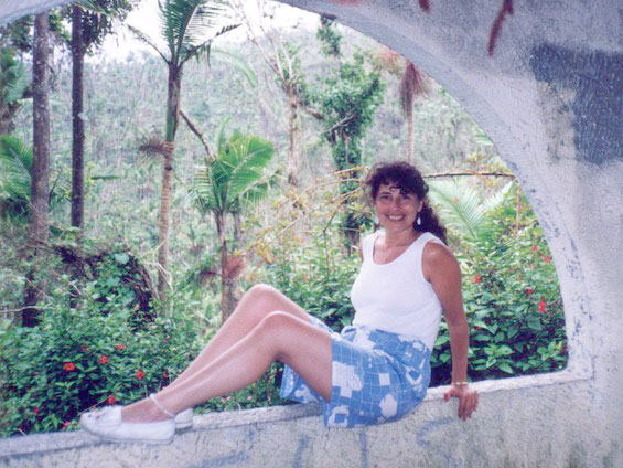 Leslea perches on a windowsill with tropical trees in the background