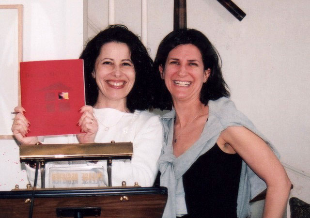 Tzivia and Leslea holding a book and smiling