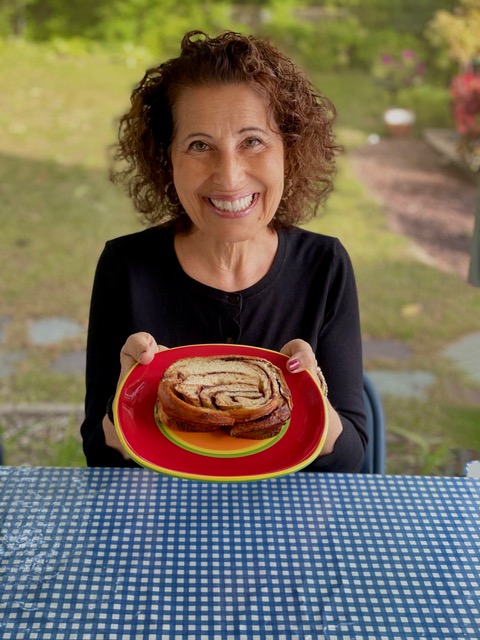 Lesléa smiles while holding a plate of babka