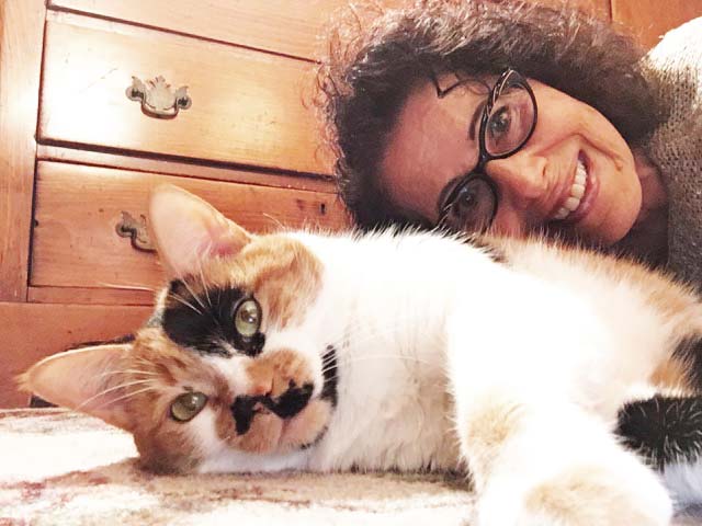 Leslea and Mitzi, her calico cat, lie on the floor to take a selfie